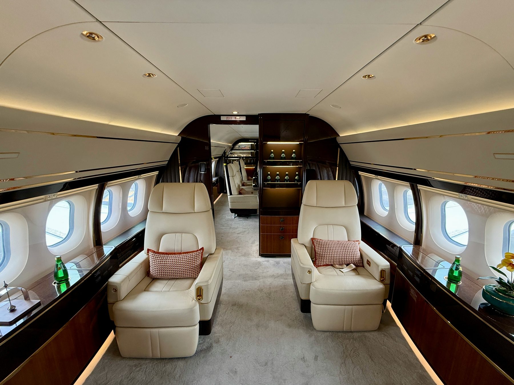 Long-range private jet cabin with cream leather seats and a bar